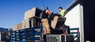 Men stacking metal items on truck