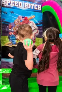 Kids playing the Speed Pitch ball toss arcade game at Bounce City Idaho Falls