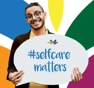 male holding a sign saying selfceare matters