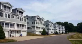 Six tall condominiums sit in a row under a gentle cloud cover.