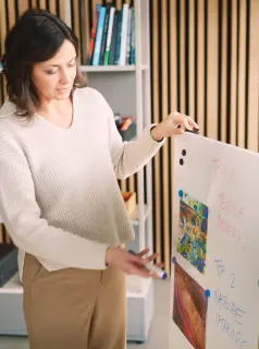 rau präsentiert Ideen an Whiteboard mit Bildern und Notizen