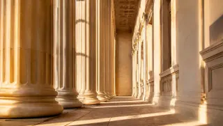 Sunlit limestone colonnade of a classical financial institution