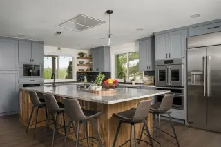 Modern kitchen with gray shaker cabinets, large wood island, quartz countertops, and stainless steel appliances
