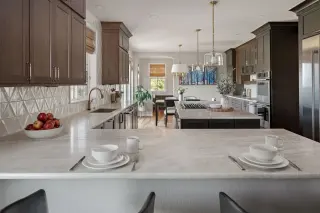 Open-concept kitchen with dark wood cabinetry, light stone countertops, a large island, and breakfast bar seating.