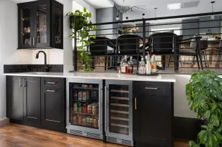 Custom bar area with black cabinetry, glass display cabinets, small sink