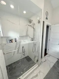 Modern shower with large white tiles and a sleek glass