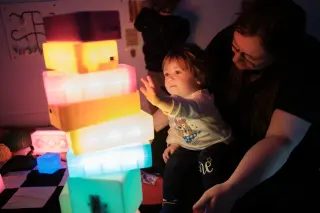 Child reaching for lit-up stack of bricks