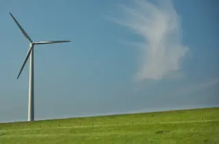 White wind turbine on green hillside