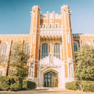 Historic university building with intricate brick and stone architecture under clear blue sky.