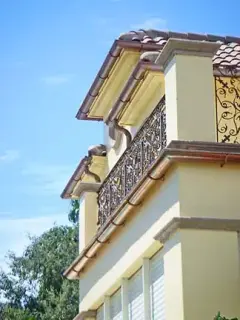 Copper gutters and downspouts on a Mediterranean home with an iron balcony