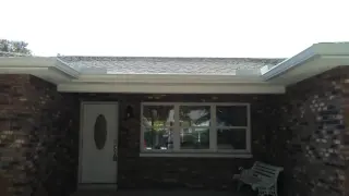 White seamless gutter across the front of a brick ranch home