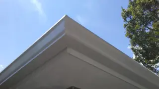 Mitred corner of a white seamless gutter against a blue sky