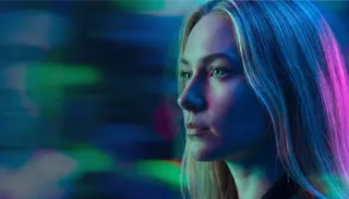 Profesional observando una pantalla entre luces de neón azules y magenta