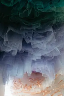 Close-up of layered pastel-colored tulle fabric in shades of green, purple, and peach.