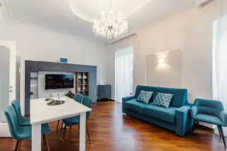 Soggiorno luminoso con lampadario di cristallo e divani teal